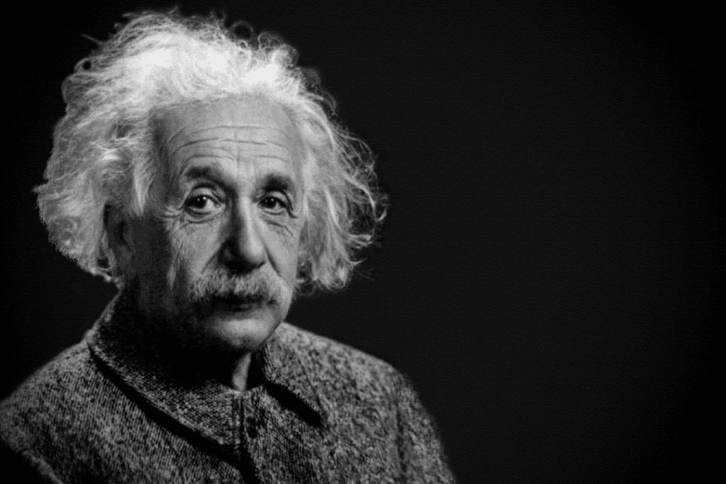 Black and white head and shoulders photo of Albert Einstein, who is looking at the camera wearing a coat.