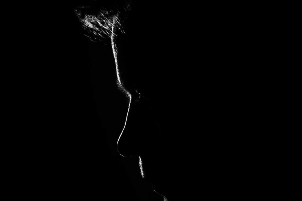 Side profile of a man's face, dimly lit.