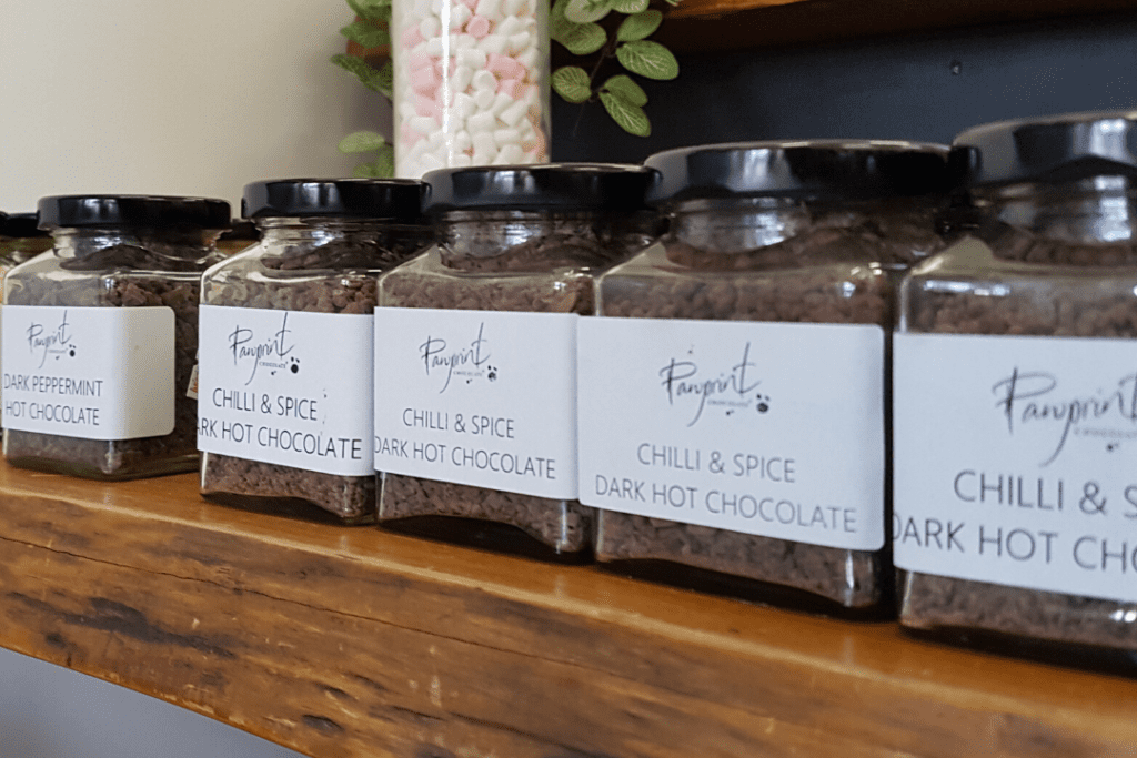 Chocolate flavours in jars at Pawprint Chocolate shop in Denmark Western Australia. The jars are on a wooden shelf with a jar of marshmallows in the background.